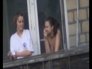 two girls smoking on the balcony in the opposite house, one with bare boobs